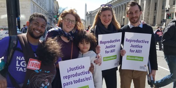 A group of 5 people holding signs that say "¡Justicia reproductiva para todas/os!" and "Reproductive Justice for All!"