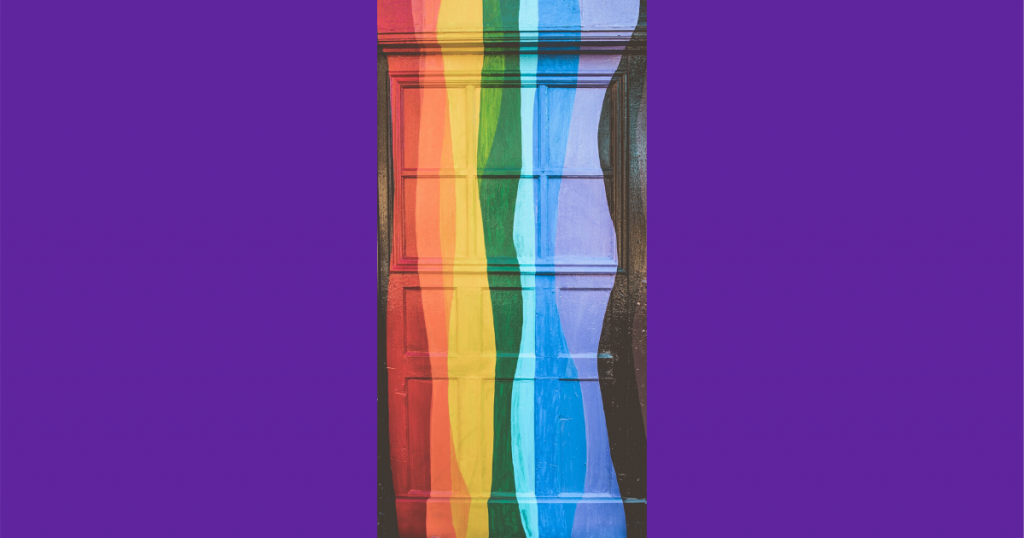 A photo of a doorway painted with a wavy vertical rainbow flag. The photo is on a purple background.