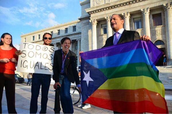 People celebrating nondiscrimination bill in Puerto Rico holding a sign and flag