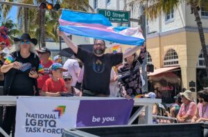 man holding q flag in a lgtbq parade
